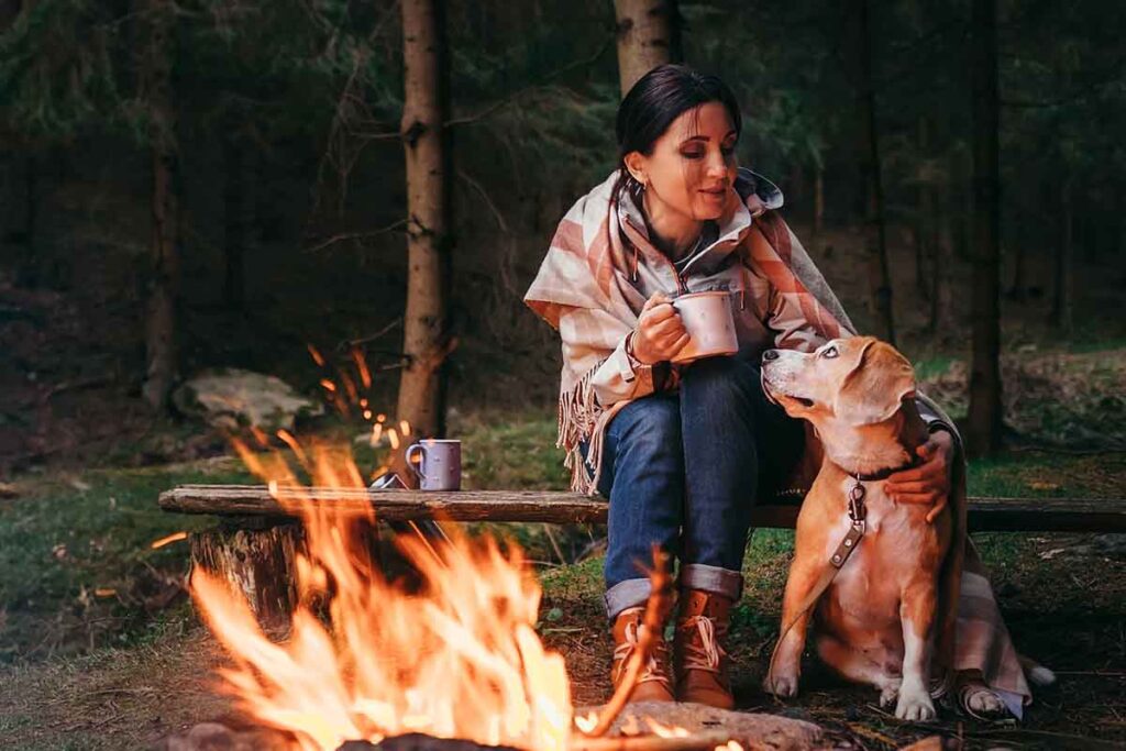 Dog and owner enjoying outdoors near camp fire